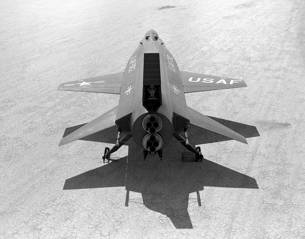 An X-15 on the dry lakebed seen from above and behind, showing the wedge-section fins, the open speed brakes and the horizontal stabilisers set with anhedral