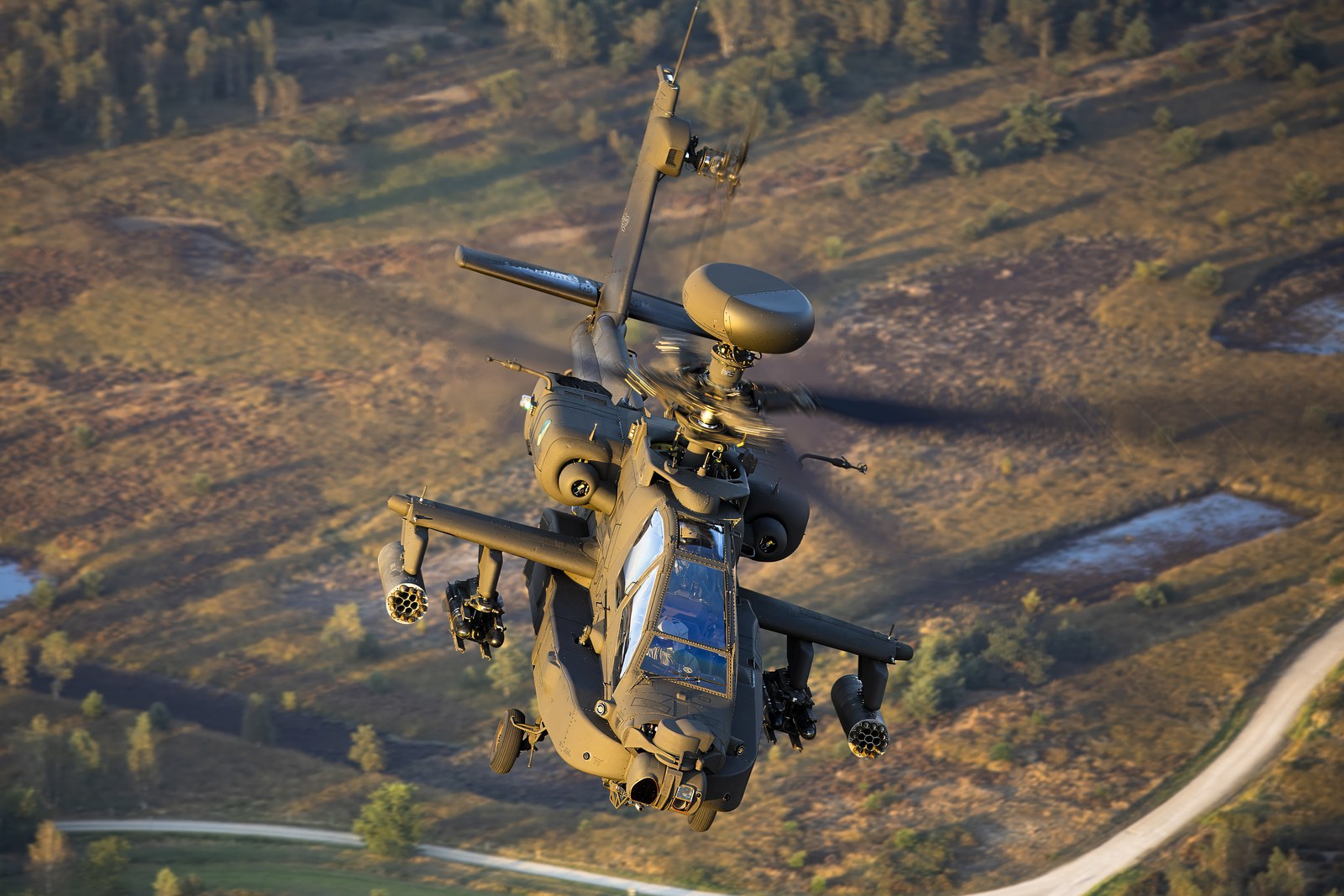 A Royal Netherlands Air Force AH-64E Apache Guardian banking over forest, seen from above