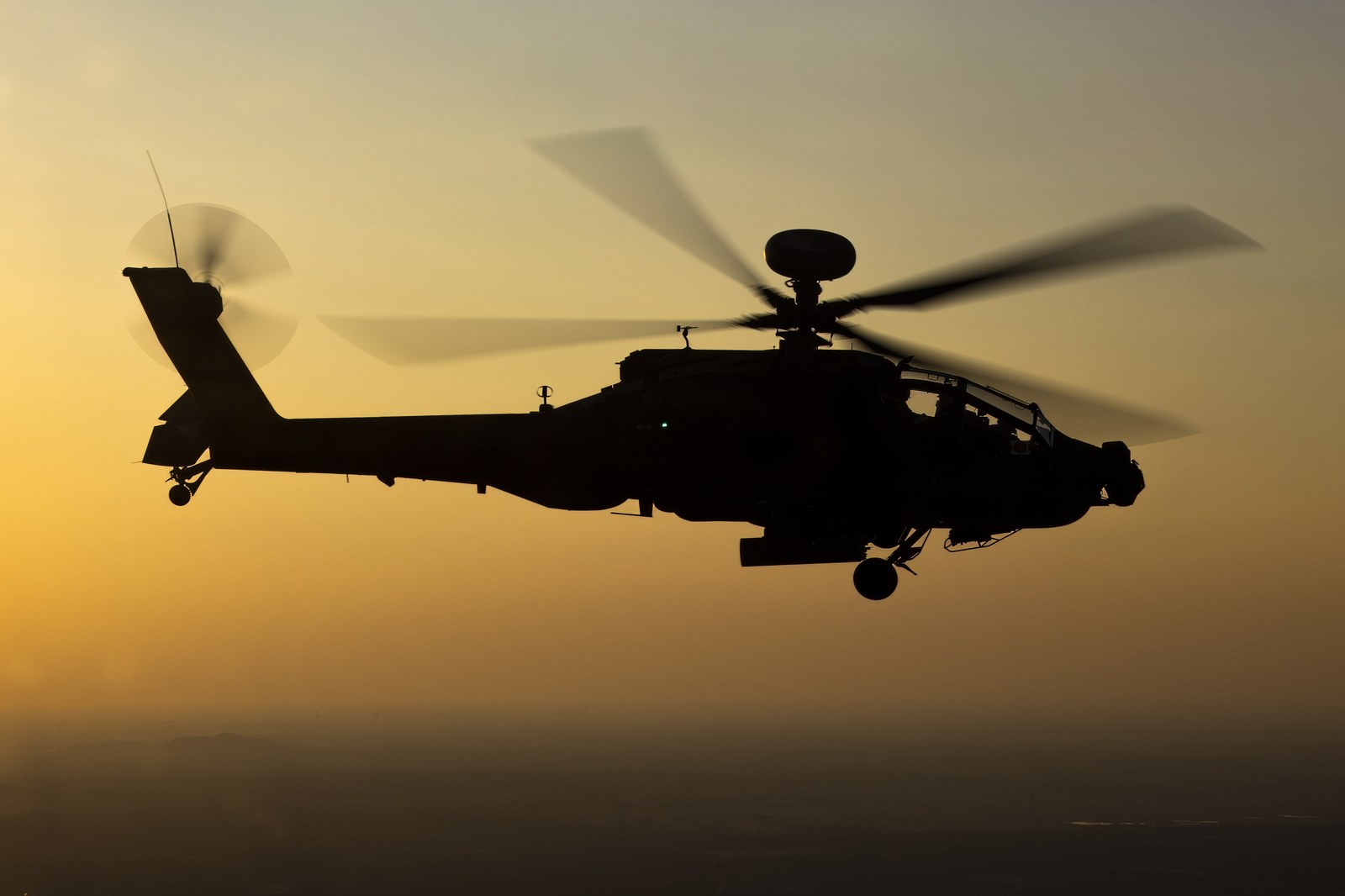 A Royal Netherlands Air Force AH-64E Apache Guardian in flight at dusk