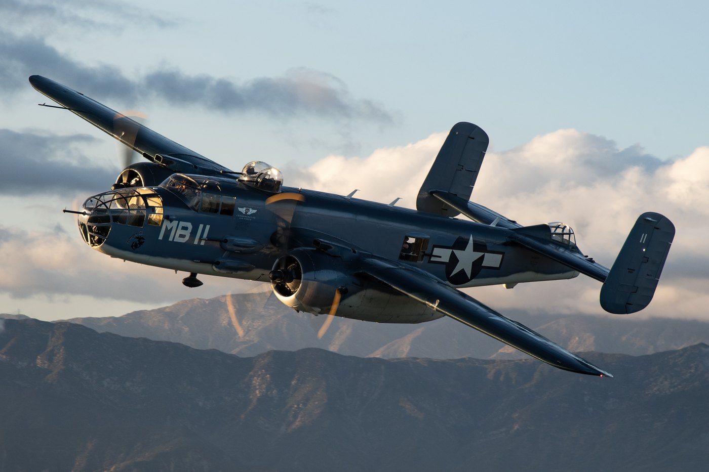 Commemorative Air Force PBJ-1J Mitchell N5865V in United States Marine Corps colours with the code MB 11, in flight over mountains at sunset
