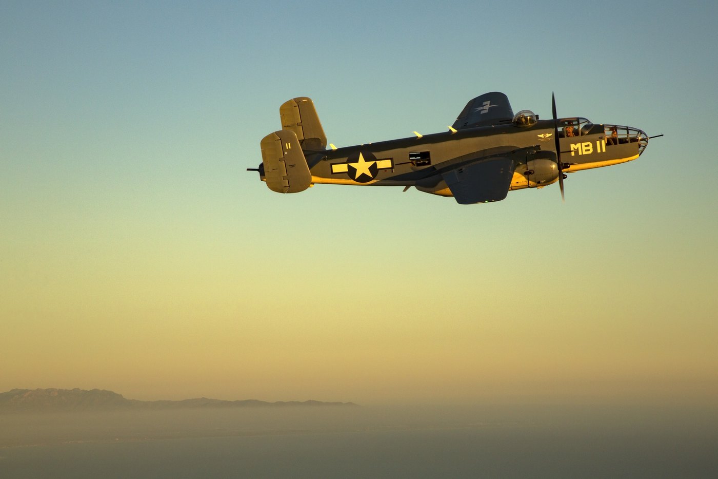 PBJ-1J Mitchell N5865V in Marine markings silhouetted in low evening light above the coastal ranges