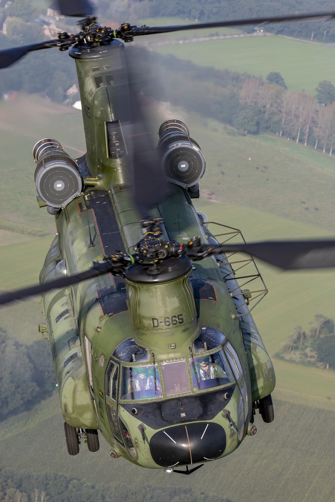 A Royal Netherlands Air Force CH-47D Chinook seen from directly above and ahead, with both pilots visible through the windscreen