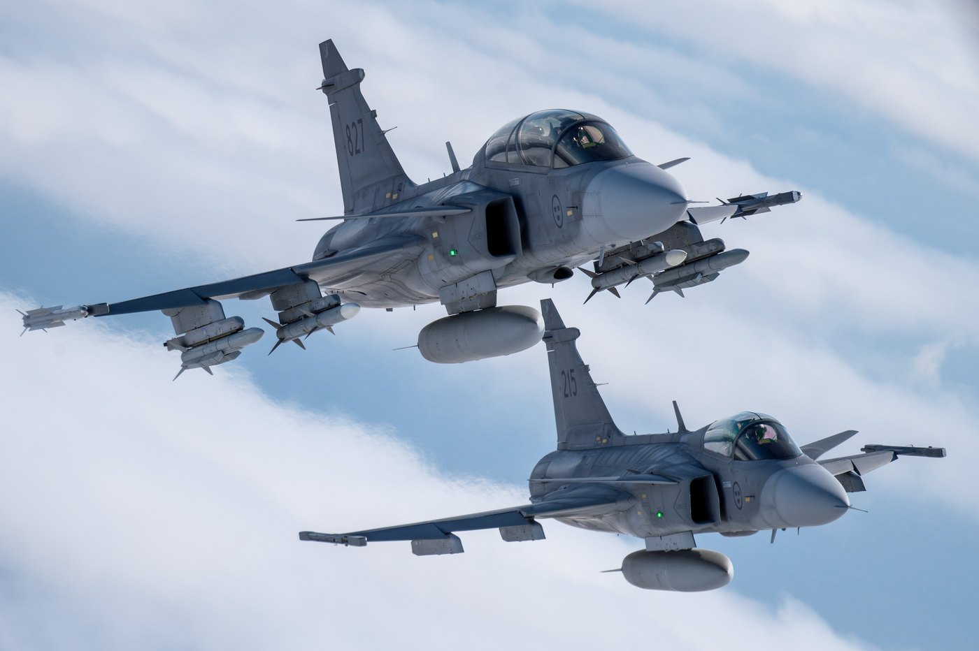 A Saab JAS 39D two-seat Gripen, 39827, leading a single-seat JAS 39C, 39215, both of the Swedish Air Force, armed and in formation