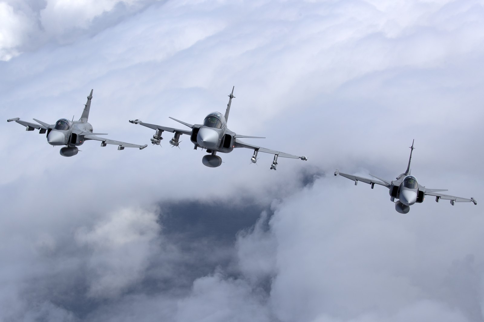 Three Swedish Air Force Saab JAS 39 Gripens, one of them a two-seat D model, flying head on through cloud