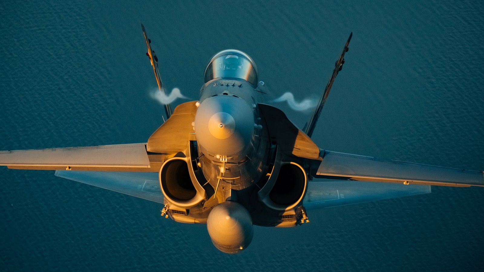 A Swiss Air Force McDonnell Douglas F/A-18C Hornet seen head on from above, with vortices streaming off both leading edge extensions