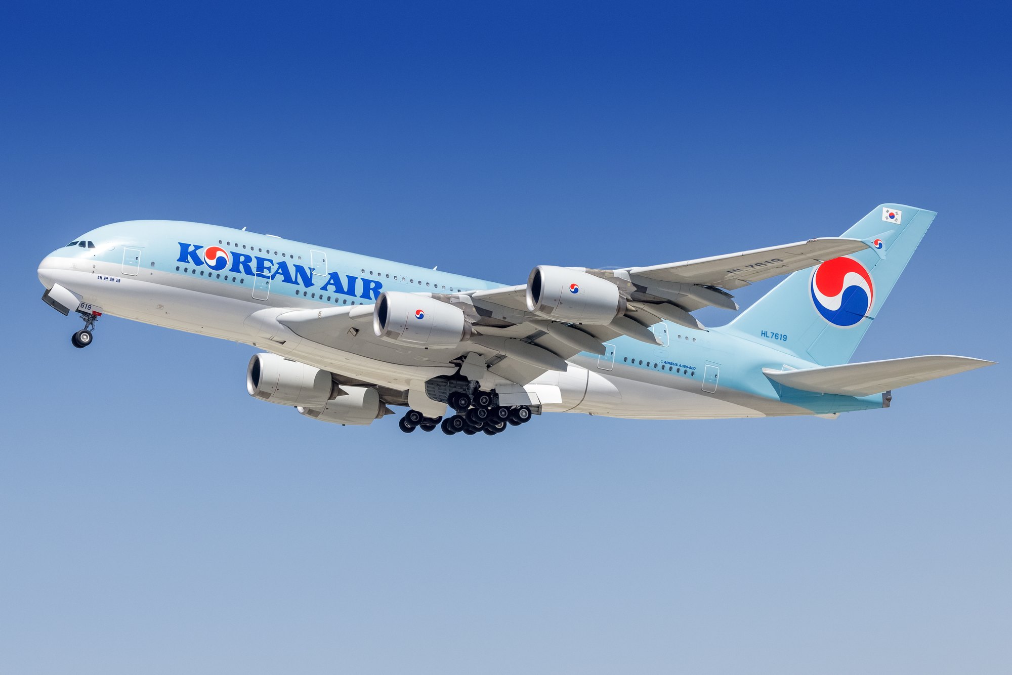 A Korean Air Airbus A380-800, registration HL7619, in pale blue and white livery, climbing away from Los Angeles with the nose gear still extended.