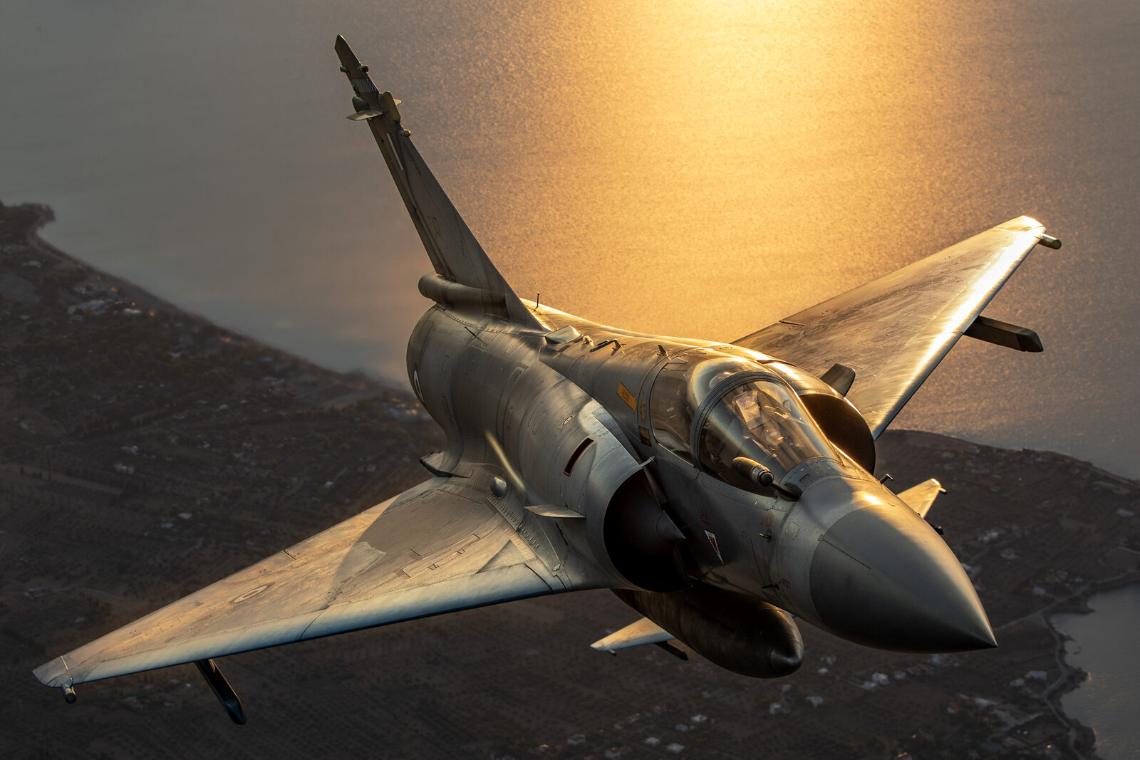 A Hellenic Air Force Dassault Mirage 2000-5EG seen from above against sunlight on the sea, showing the delta planform
