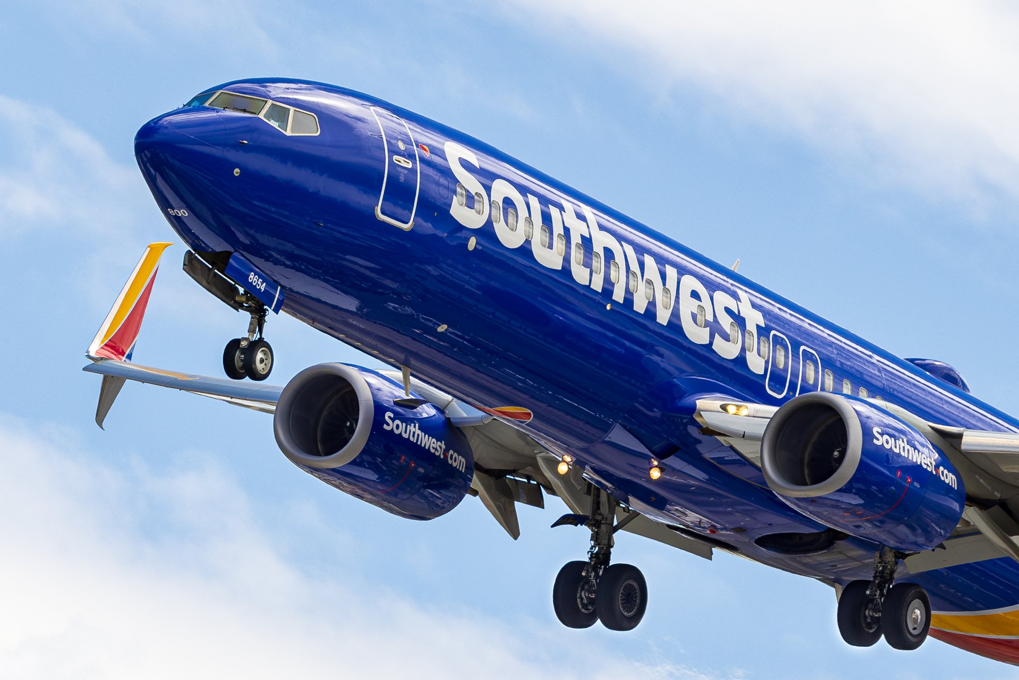 A Southwest Airlines Boeing 737 MAX 8 seen from close to head-on, gear down, filling the frame against light cloud.