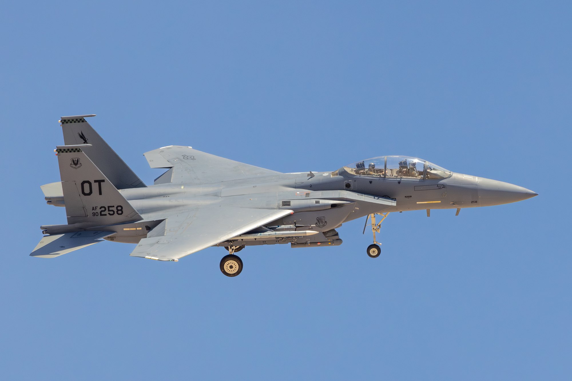 A US Air Force F-15E Strike Eagle, tail code OT, serial 90-258, on approach with the undercarriage down against a pale blue sky.